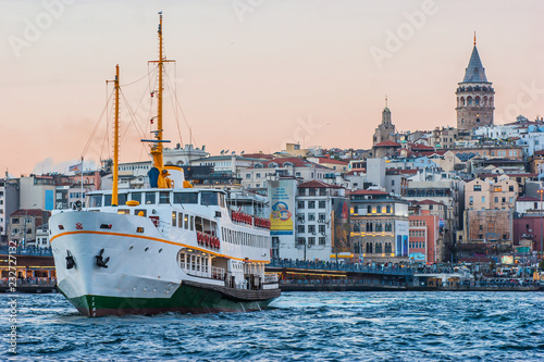 Galata Tower and Galata Bridge with steamship or steamboat at night scene on Golden Horn Eminonu which is famous tourist area Istanbul, Turkey