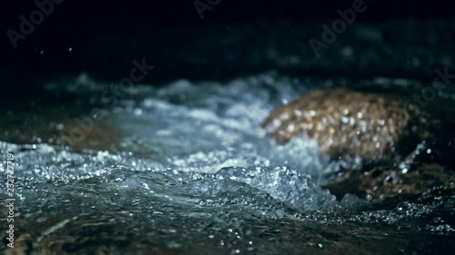 Slow motion of waves on dark water surface with play of flecks of bright light close up. Amazing dramatic natural background. Shooting with 180fps. Epic mystical and magic night view. Crystal clear