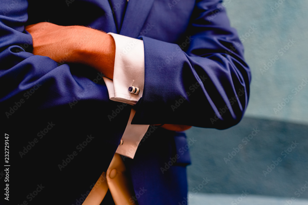 Crossed arms of businessman with blue suit.