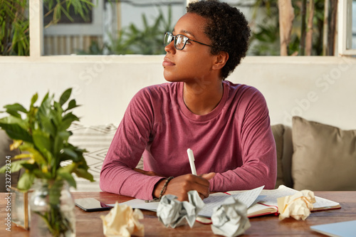 Fotografi Thoughtful black girl in eyewear focused aside, tries to gather with thoughts, w