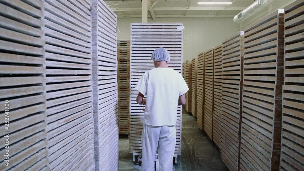 WARSAW, POLAND - JULY 25, 2018: Factory worker pushing cart with candies in storage room.