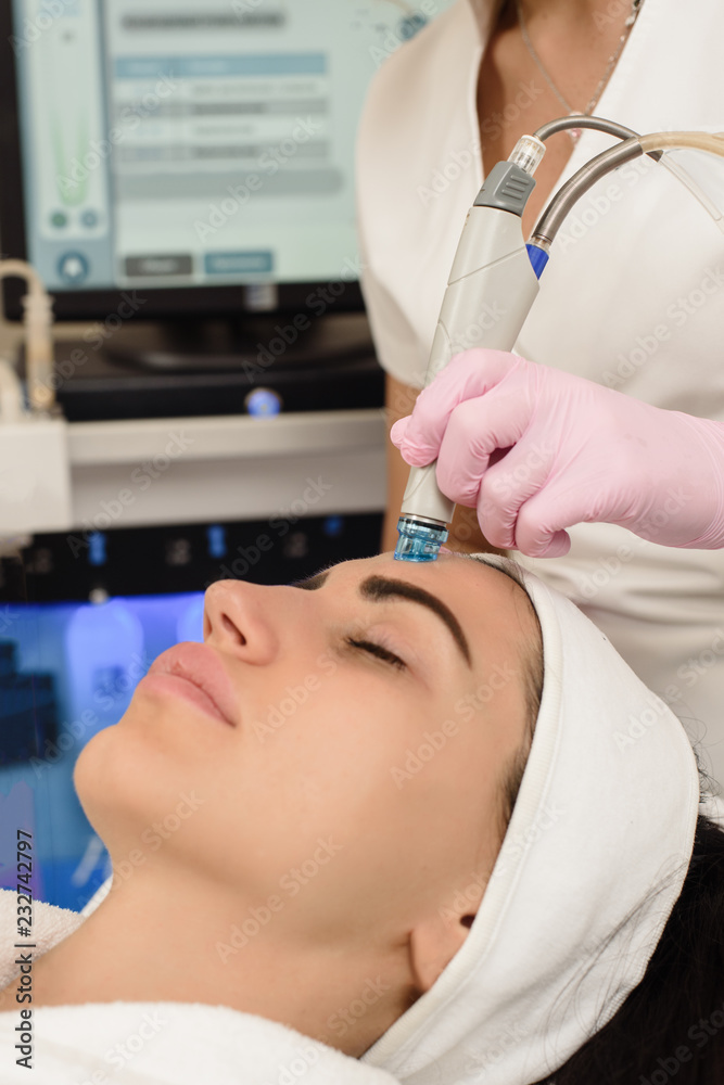 Young woman having ultrasound face peeling in spa salon