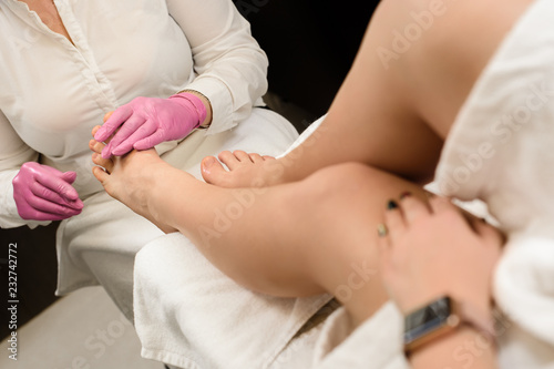 Masseur making feet massage for young woman in spa salon