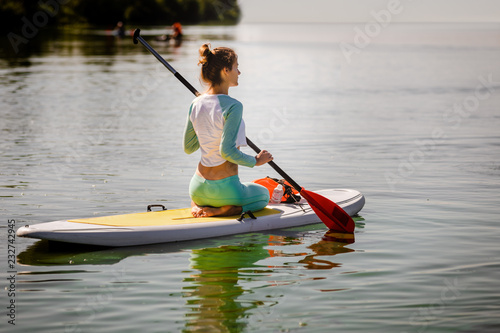 Young woman on sup board with paddle on summer day