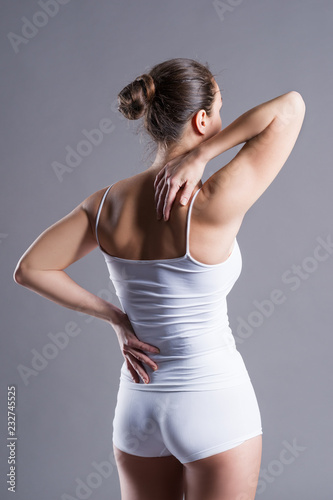 Back pain, woman with backache on gray background