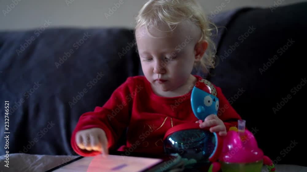 Baby playing with mobile device and watching tv , eating Baby playing with mobile device and watching tv , eating
