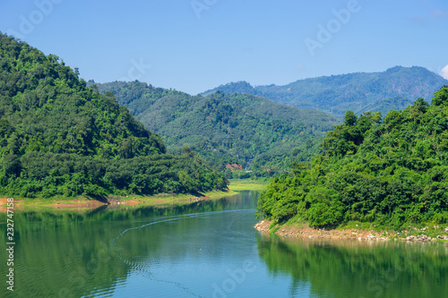 View of Bang Lang Dam water between two mountains and clear blue sky.