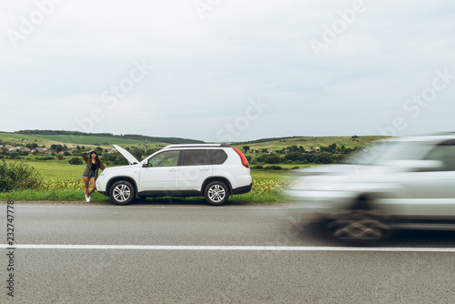 woman stand at roadside near broken car with opened hood © phpetrunina14