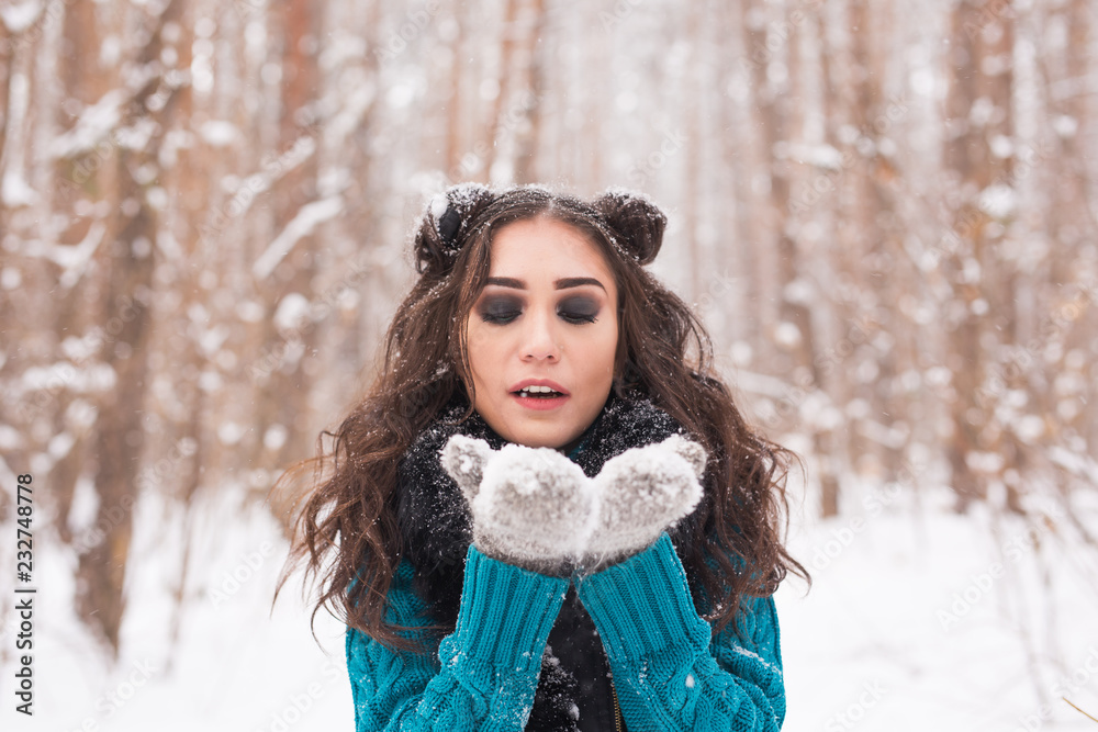 Christmas, holidays and season concept - Young happy brunette woman blowing snow in the winter nature Christmas, holidays and season concept - Young happy brunette woman blowing snow in the winter nature