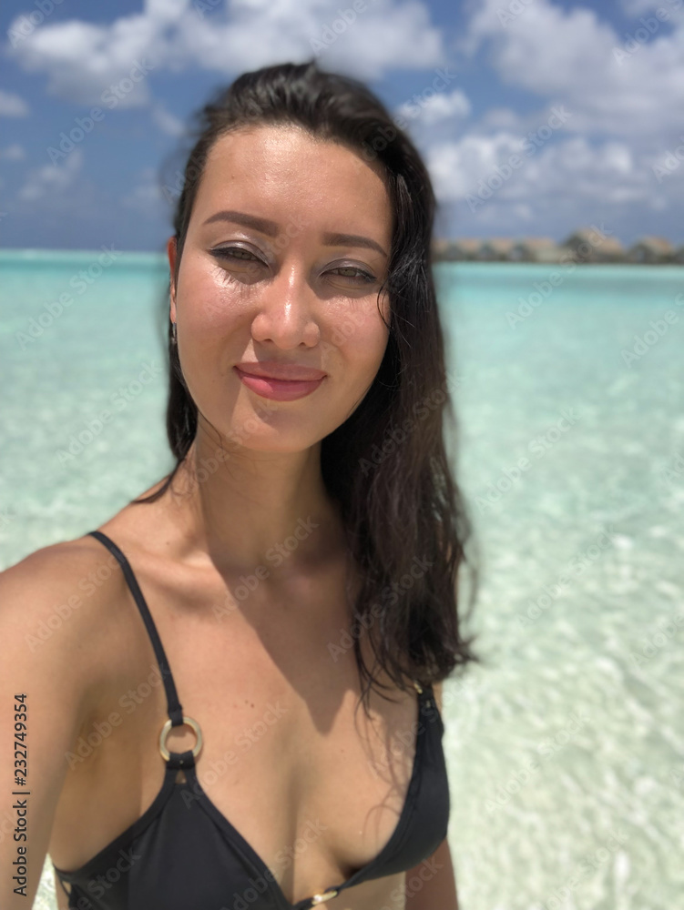 portrait of a beautiful tanned girl in a bikini on the beach in the Maldives