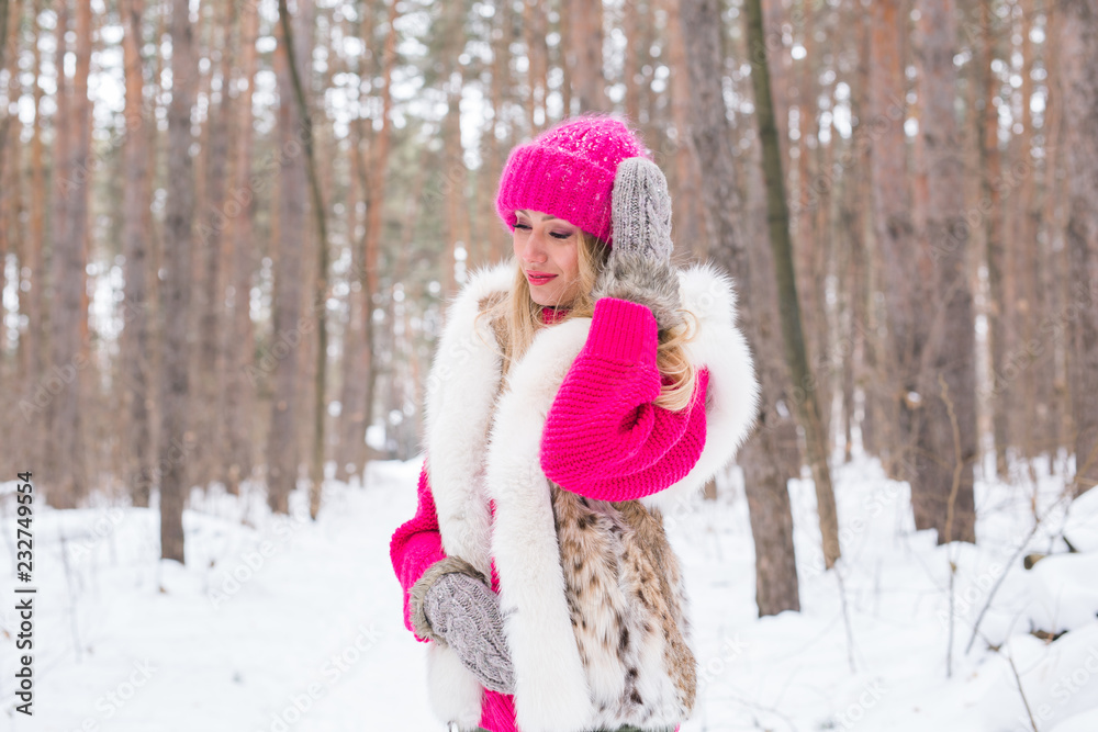 Beauty, fashion and people concept - Attractive blond woman standing in pink hat and sweaters in winter wood and smiling