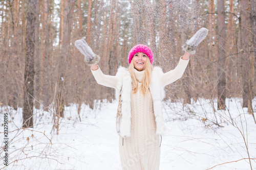 Fun, winter and people concept - Attractive young woman dressed in coat throwing snow.