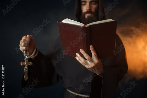 Medieval monk praying with book in church