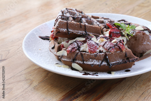 Close up of chocolate ice cream with waffle and fresh strawberry on wood table background