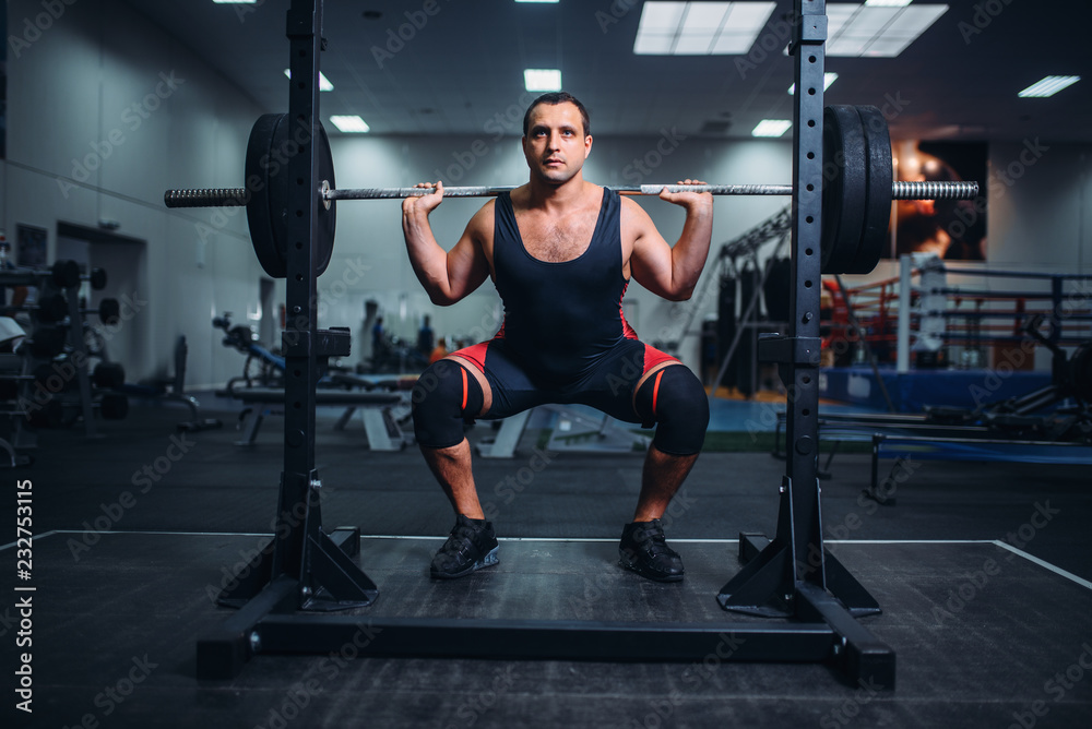 Powerlifter doing squats with barbell in gym Powerlifter doing squats with barbell in gym