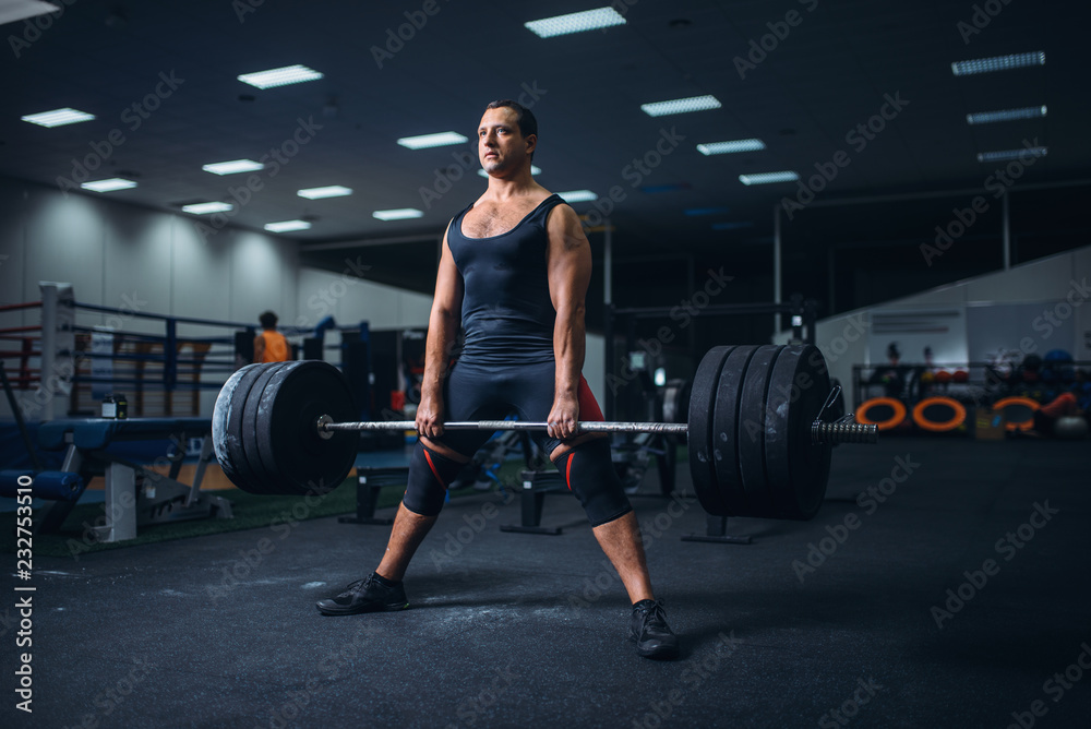Male powerlifter preparing deadlift barbell in gym Male powerlifter preparing deadlift barbell in gym