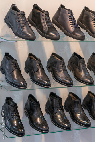 Men's leather shoes on the shelf in the store. Racks in the store of clothes and accessories. Shelves with stylish men's shoes. Many classic shoes and boots. vertical photo.