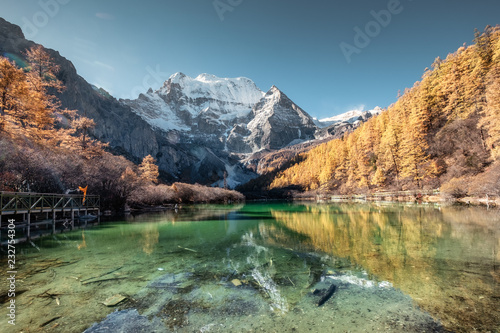 Fototapeta Naklejka Na Ścianę i Meble -  Xiannairi mountain reflection on emerald lake with golden pine forest in autumn