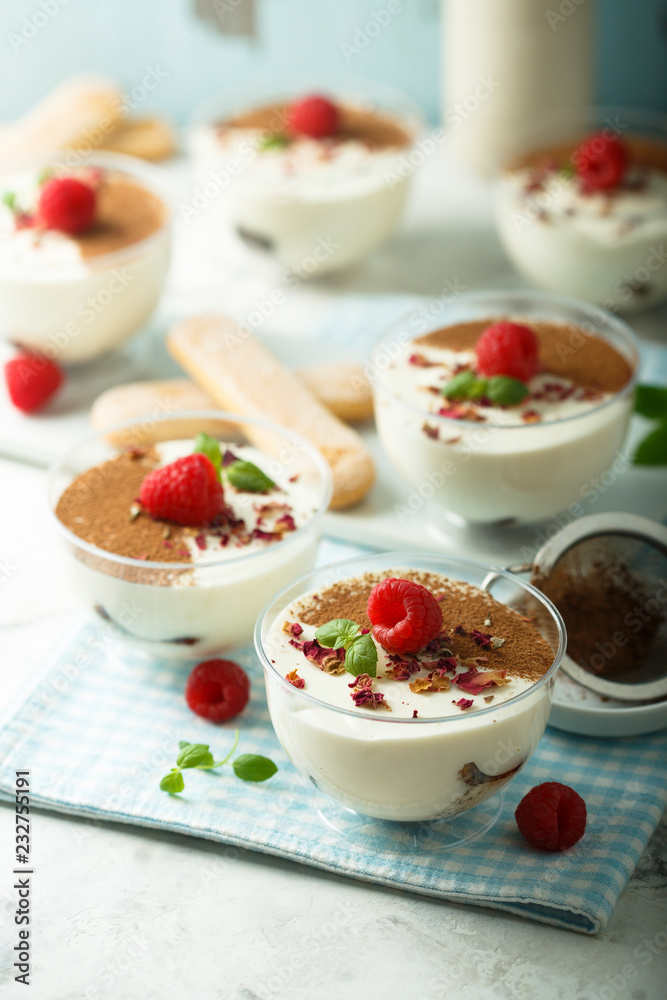 Homemade tiramisu dessert decorated with fresh raspberry and rose petals Homemade tiramisu dessert decorated with fresh raspberry and rose petals