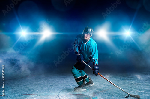 One hockey player on ice, spotlights on background