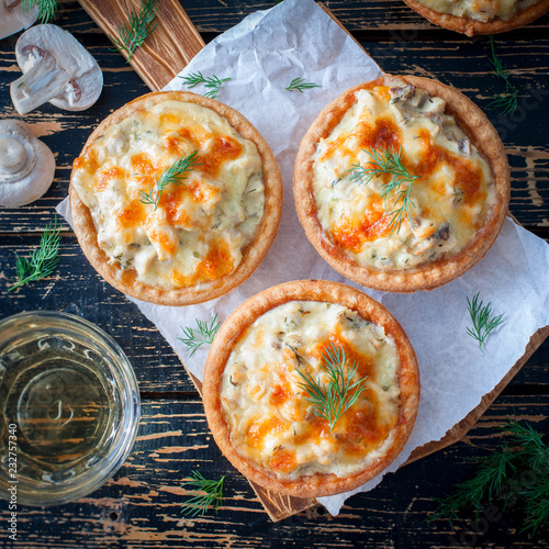 Tartlets with mushrooms, chicken and cheese on a wooden board, top view, square