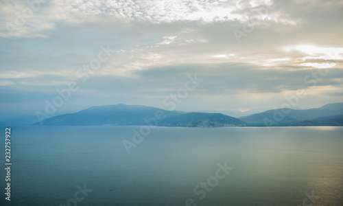abstract mountain landscape background horizon silhouettes in morning foggy weather time near calm and quiet sea cape water surface