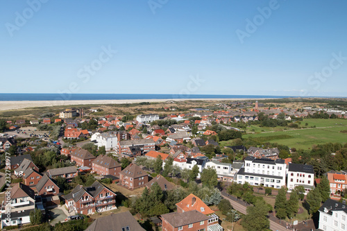 blick auf gebäude sowie grünen landstrich mit der nordsee und dem strand am horizont auf der nordsee insel borkum fotografiert während einer sightseeing tour auf der insel bei strahlendem sonnenschein