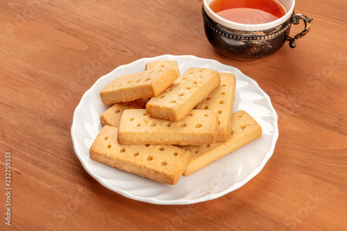 A photo of Scottish shortbreads, butter cookies on a rustic background with a vintage tea cup and copy space