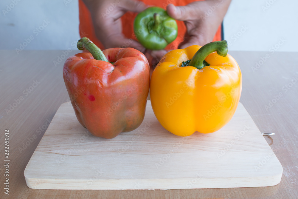 Fresh colorful bell pepper cooking on wooden cut board in kitchen table ready for cook Fresh colorful bell pepper cooking on wooden cut board in kitchen table ready for cook