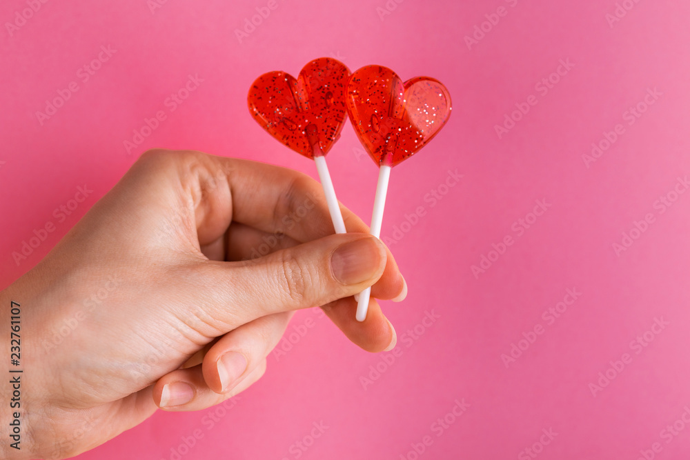 Two sweet bright red lollipops in woman's hand