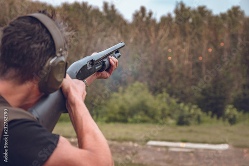 man in soundproof headphones shoots a hard disk at flying plates