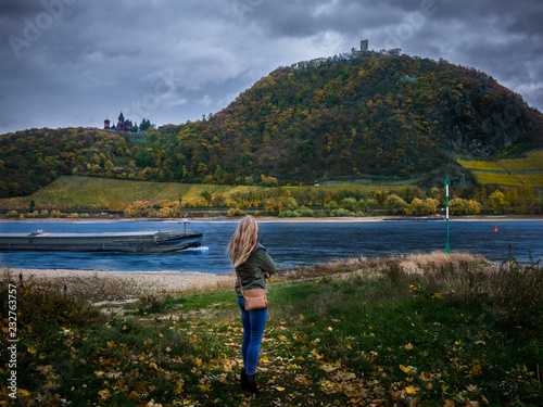 young girl next to a river and looking at a castle on the mountain