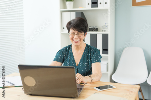 Business, web design and graphic art concept - Middle age woman working at the office with the smile on her face