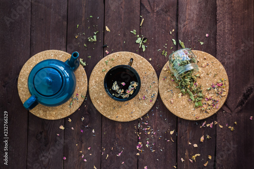 a small blue teapot, a mug of tea and dry herbal tea on a wooden background. Herbal medicine. tea from flowers.