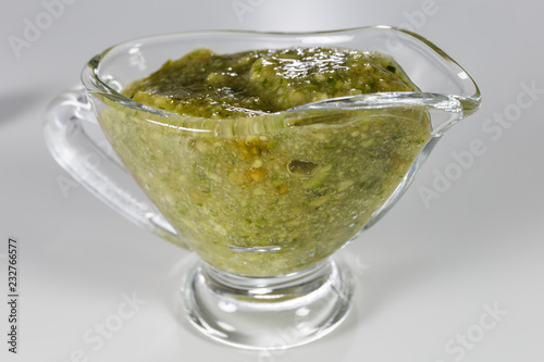 Sauce pesto in glass sauceboat isolated on white.