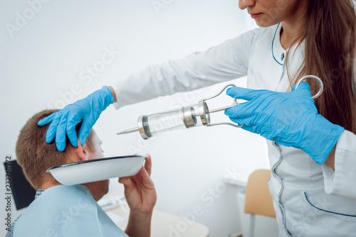 Medical ear washing with water in big syringe