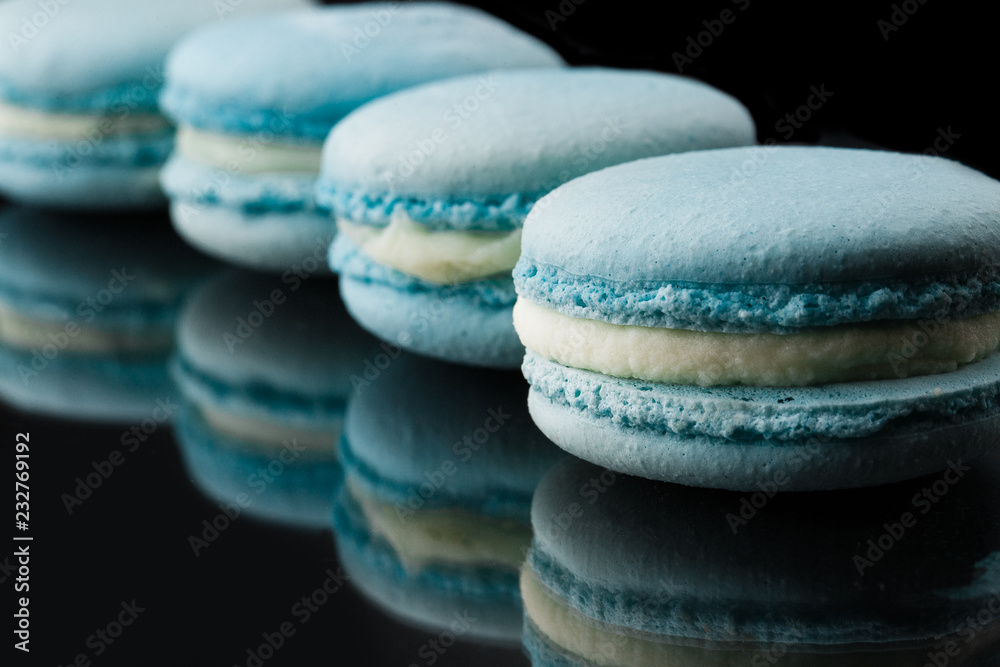 French macarons. Stack of blue macaron with dorblu and wine isolated on dark mirror background. Colorful macaroons. Top view