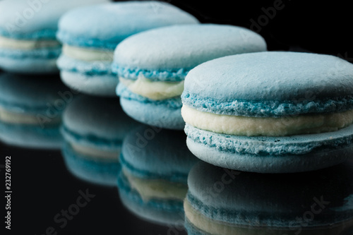 French macarons. Stack of blue macaron with dorblu and wine isolated on dark mirror background. Colorful macaroons. Top view