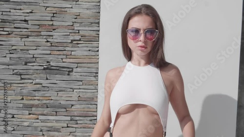 Sexy woman in swimsuit and sunglasses posing outdoor by the pool - video in slow motion