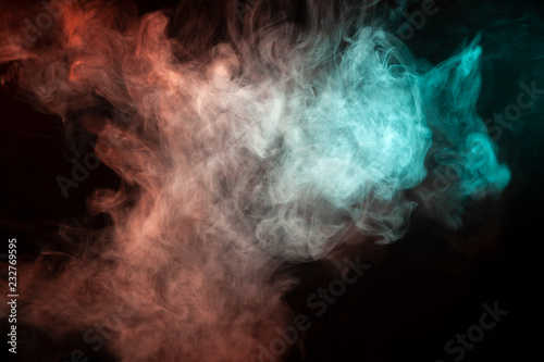 Multicolored smoke from a vape of green and red color of the strange mystical form on on a black isolated background. Bright clouds in the abstract form.
