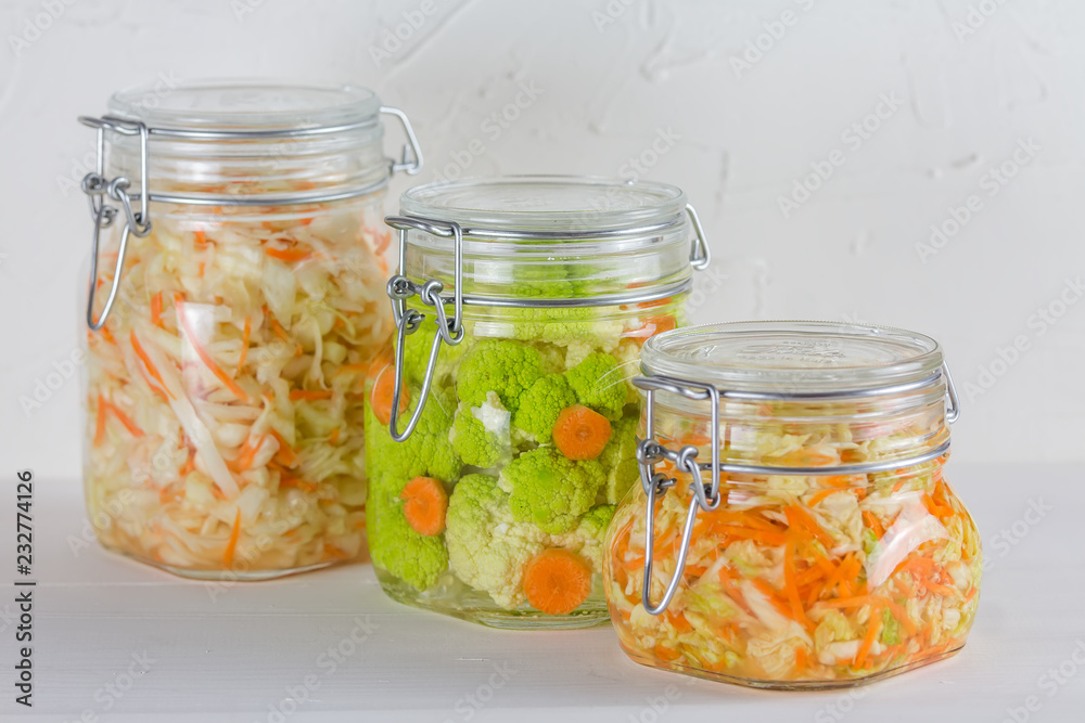 Fermented preserved vegetarian food concept. Cabbage, broccoli, caulie, sauerkraut sour glass jars on white background Fermented preserved vegetarian food concept. Cabbage, broccoli, caulie, sauerkraut sour glass jars on white background