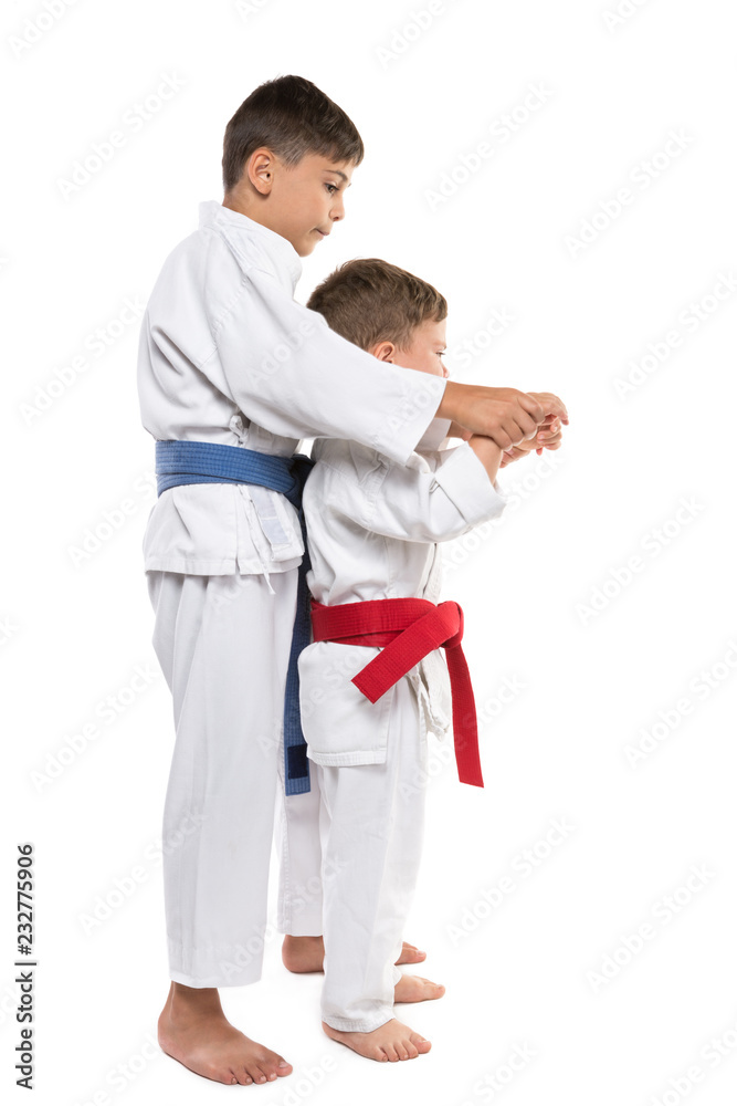 two boys in karate training, the eldest helps the younger, brothers, on a white background, isolate