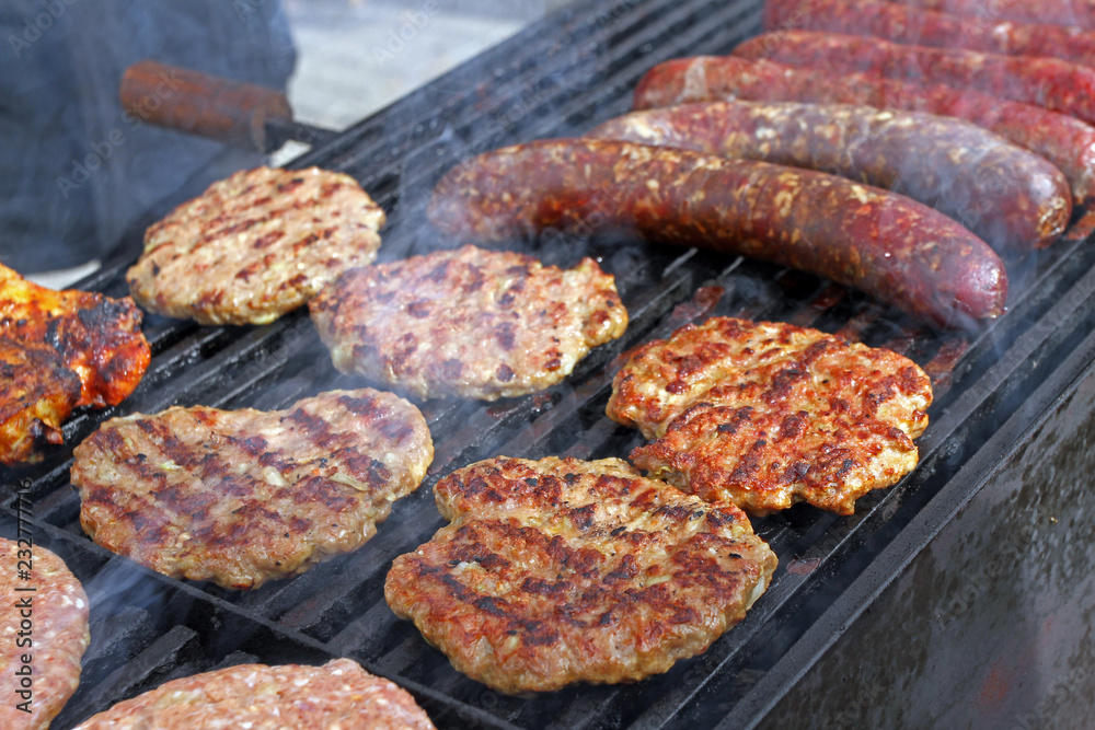 Grilling sausages, burgers, pork steak on barbecues gas grill for party. Hot dogs,sausages and hamburgers on a barbeque, bbq. Smokes meat food outdoors, fast food. Hamburgers. Pleskavitsa Grilling sausages, burgers, pork steak on barbecues gas grill for party. Hot dogs,sausages and hamburgers on a barbeque, bbq. Smokes meat food outdoors, fast food. Hamburgers. Pleskavitsa