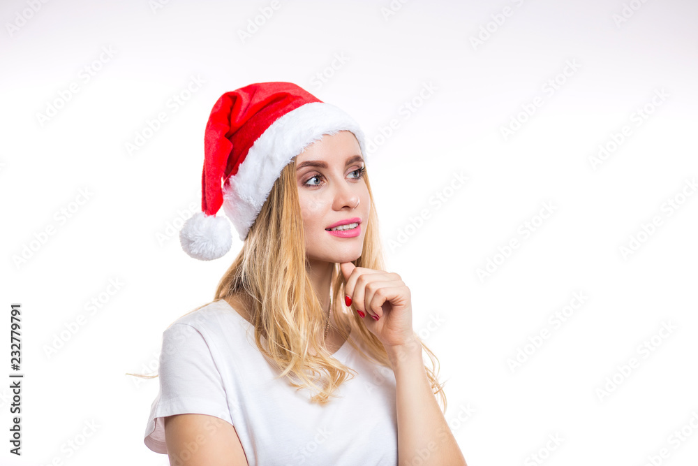 Happy charming blonde woman in red Santa hat and t-shirt looking with smile to the side on white background Happy charming blonde woman in red Santa hat and t-shirt looking with smile to the side on white background