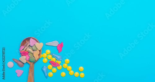 Top view of pharmaceutical medicine pills, capsules and tablets w/ wooden spoon on light blue background. Vitamin and supplement. Health behavior concept. Minimal style. Creative idea.