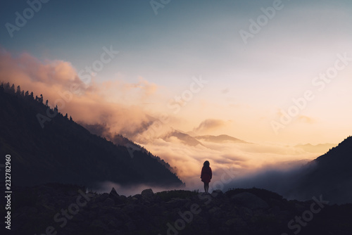 Silhouette of a woman standing on a ridge  enjoying the sunset.