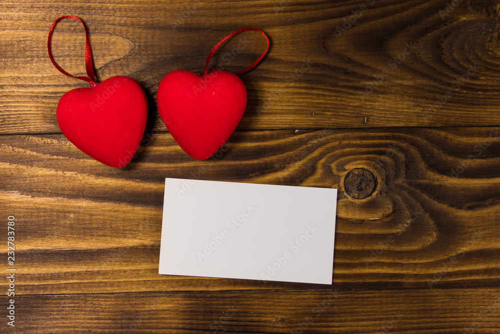 Valentine's day blank greeting card and two red hearts on wooden background Valentine's day blank greeting card and two red hearts on wooden background