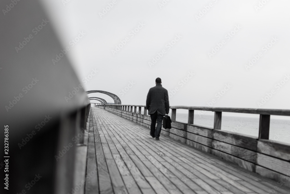 Mann mit Tasche auf Seebrücke