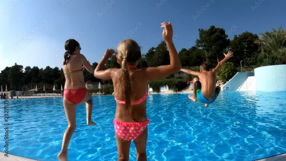 Three kids jumping in the pool, filmed in slow motion