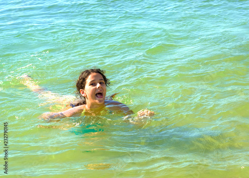 The brunette girl is joyfully swimming in sea water
